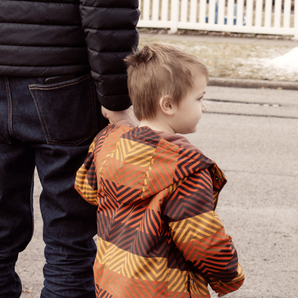 A father holds his young son's hand to cross the street
